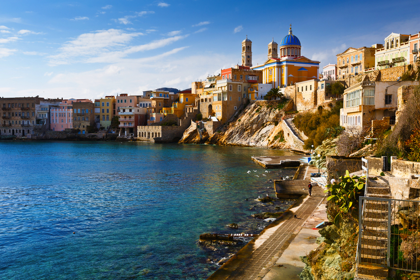 Küstenstadt mit bunten Häusern und Kirche am Wasser.