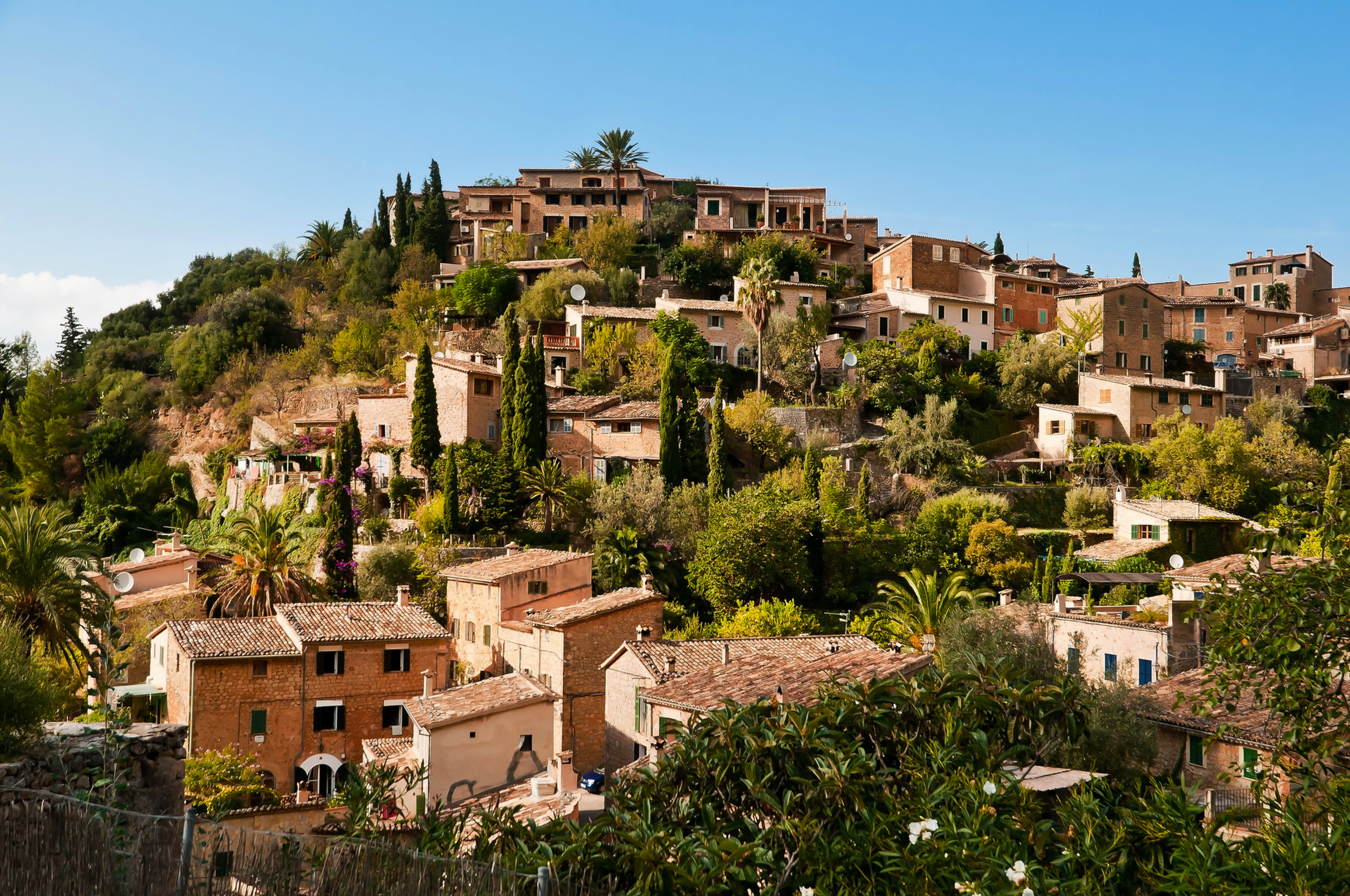 Mittelalterliches Dorf auf einem Hügel, umgeben von mediterraner Vegetation.